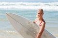 Young attractive surfer holds a board on the beach