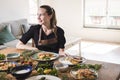 Young attractive swedish food blogger posing in front of a table full of food dishes. Young girl sitting in front of a wooden Royalty Free Stock Photo