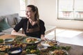 Young attractive swedish food blogger posing in front of a table full of food dishes. Young girl sitting in front of a wooden Royalty Free Stock Photo