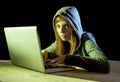 Young attractive teen woman wearing hood on hacking laptop computer cybercrime cyber crime concept