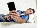 Young attractive tired and overworked falling asleep at home couch with mobile phone and digital tablet pad