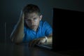 Young attractive and tired unshaven man working late night on laptop computer in the dark feeling frustrated and exhausted in