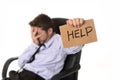 Young attractive tired and wasted businessman sitting on office chair asking for help in stress Royalty Free Stock Photo