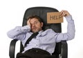 Young attractive tired and wasted businessman sitting on office chair asking for help in stress Royalty Free Stock Photo