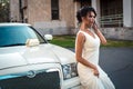 Young attractive VIP Woman in the dress stand near white limousine