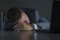 Young attractive wasted and tired entrepreneur man sleeping taking nap late night at office laptop computer desk exhausted in Royalty Free Stock Photo