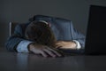 Young attractive wasted and tired entrepreneur man sleeping taking nap late night at office laptop computer desk exhausted in Royalty Free Stock Photo