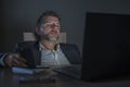 Young attractive wasted and tired entrepreneur man sleeping taking nap late night at office laptop computer desk exhausted in Royalty Free Stock Photo