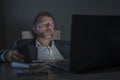 Young attractive wasted and tired entrepreneur man sleeping taking nap late night at office laptop computer desk exhausted in Royalty Free Stock Photo