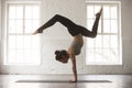 Young attractive woman in Adho Mukha Vrksasana pose, white studi