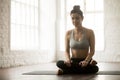 Young attractive woman in Agni stambhasana pose, white loft stud