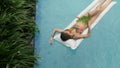 Young attractive woman bathes in a pool on a mattress. view from above. woman on vacation swims in her pool