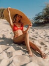 Young attractive woman in bikini with big straw hat posing at sandy beach Royalty Free Stock Photo