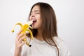 Young attractive woman biting banana in tempting manner looking seductive standing on isolated white background dietology and