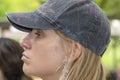 Young attractive woman with blond hair and a worn cap on her head - side view with a slight pout and a little sheen of sweat