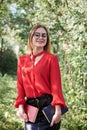 Young attractive woman with blond short hair, wearing red shirt and black skirt, holding books in her hands. Three-quarter Royalty Free Stock Photo