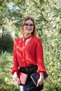 Young attractive woman with blond short hair, wearing red shirt and black skirt, holding books in her hands. Three-quarter Royalty Free Stock Photo