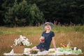 Young attractive woman in a blue dress at an outdoor picnic. A basket with daisies, watermelon, strawberries and a glass Royalty Free Stock Photo