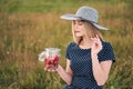 Young attractive woman in a blue dress at an outdoor picnic. A basket with daisies, watermelon, strawberries and a glass Royalty Free Stock Photo