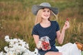 Young attractive woman in a blue dress at an outdoor picnic. A basket with daisies, watermelon, strawberries and a glass Royalty Free Stock Photo