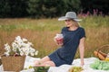 Young attractive woman in a blue dress at an outdoor picnic. A basket with daisies, watermelon, strawberries and a glass Royalty Free Stock Photo