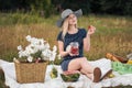 Young attractive woman in a blue dress at an outdoor picnic. A basket with daisies, watermelon, strawberries and a glass Royalty Free Stock Photo