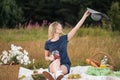 Young attractive woman in a blue dress at an outdoor picnic. A basket with daisies, watermelon, strawberries and a glass Royalty Free Stock Photo