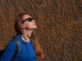 Young attractive woman in blue hoody black sunglasses on wall background listening to music with Wi-Fi headphones Royalty Free Stock Photo