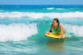 Young attractive woman bodyboards on surfboard with nice smile