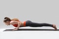 Young attractive woman in chaturanga dandasana pose, grey studio