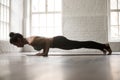 Young attractive woman in chaturanga dandasana pose, white loft