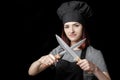 Young attractive woman chef in black uniform holds Two knives on black background Royalty Free Stock Photo