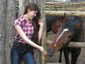 young attractive woman in cowgirl style feeding young horses Royalty Free Stock Photo
