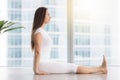 Young attractive woman in Dandasana pose against floor window