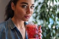 Young attractive woman drinking lemonade and looking at the camera.