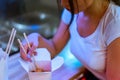 Young attractive woman eating asian food with chopsticks at cafe or restaurant. Royalty Free Stock Photo