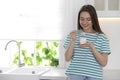Attractive woman eating tasty yogurt in kitchen. Space for text Royalty Free Stock Photo