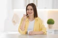 Young attractive woman eating tasty yogurt at table in kitchen Royalty Free Stock Photo