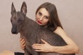 Young attractive woman embracing Mexican Hairless dog, or Xoloitzcuintle breed.