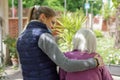 Young attractive woman embracing old grandmother outdoor. Female - generations - love