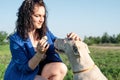 Young attractive woman feeding her dog in the park in summer day Royalty Free Stock Photo