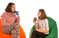 Young attractive woman and girl sitting on beanbag chairs and dr