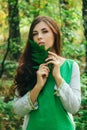 A young, attractive woman in a green dress from a medieval villager holds a fern leaf in her hands. A village herbalist collects h