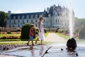 Young attractive woman and her child, refreshing with water splashes on a hot summer day in chateaux Chenonceau