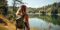 young attractive woman hiker with backpack near mountain lake. AI Generated