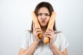 Young attractive woman holding baguette devided into two parts in both hands near her face looking upset standing on isolated Royalty Free Stock Photo