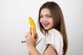 Young attractive woman holding banana like a gun in her hand looking sexy standing on isolated white background dietology and