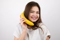 Young attractive woman holding banana like a phone in her hand looking happy standing on isolated white background dietology and