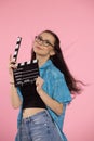 Young attractive woman holding film clapper. Teen girl in a blue shirt and glasses holding classic black film making