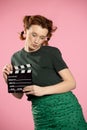 Young attractive woman holding film clapper. Teen girl in a blue shirt and glasses holding classic black film making